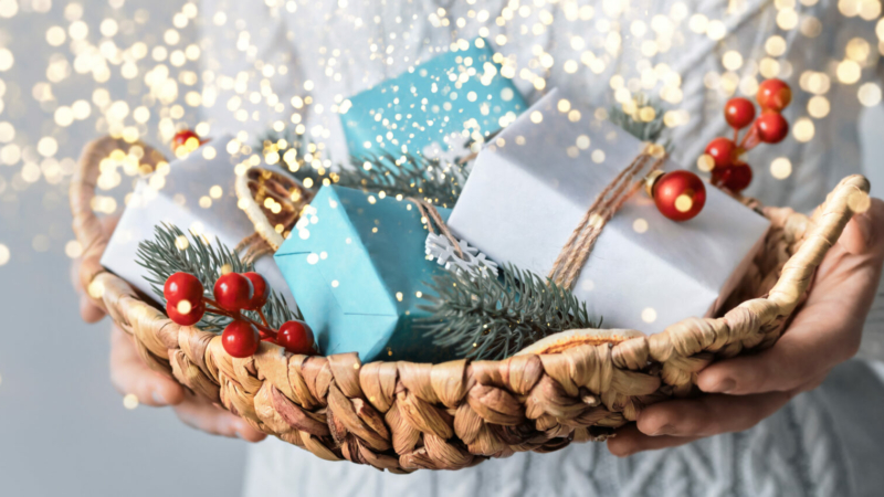 Woman holding basket with sustainable wrapped Christmas gifts, close-up, selective focus. Eco Christmas decor, banner format