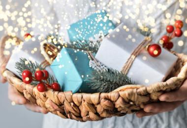 Woman holding basket with sustainable wrapped Christmas gifts, close-up, selective focus. Eco Christmas decor, banner format